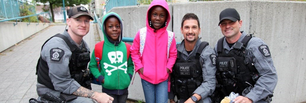 three tactical officers posing with children