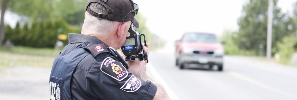 Police officer pointing speedometer at oncoming truck